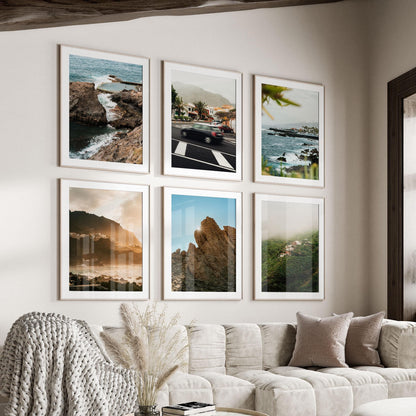 Six "Tenerife - Set of 6" framed photos hang above a beige sofa with pillows and a knit blanket.