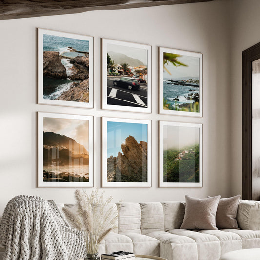 Six "Tenerife - Set of 6" framed photos hang above a beige sofa with pillows and a knit blanket.