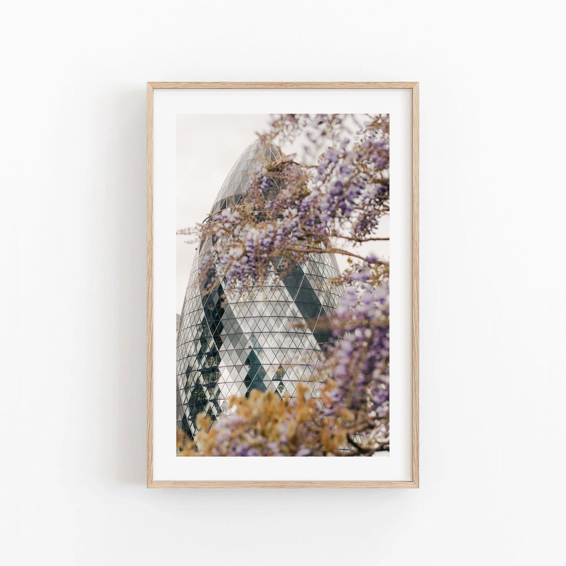 Framed photo of The Gherkin partially obscured by branches with purple flowers.