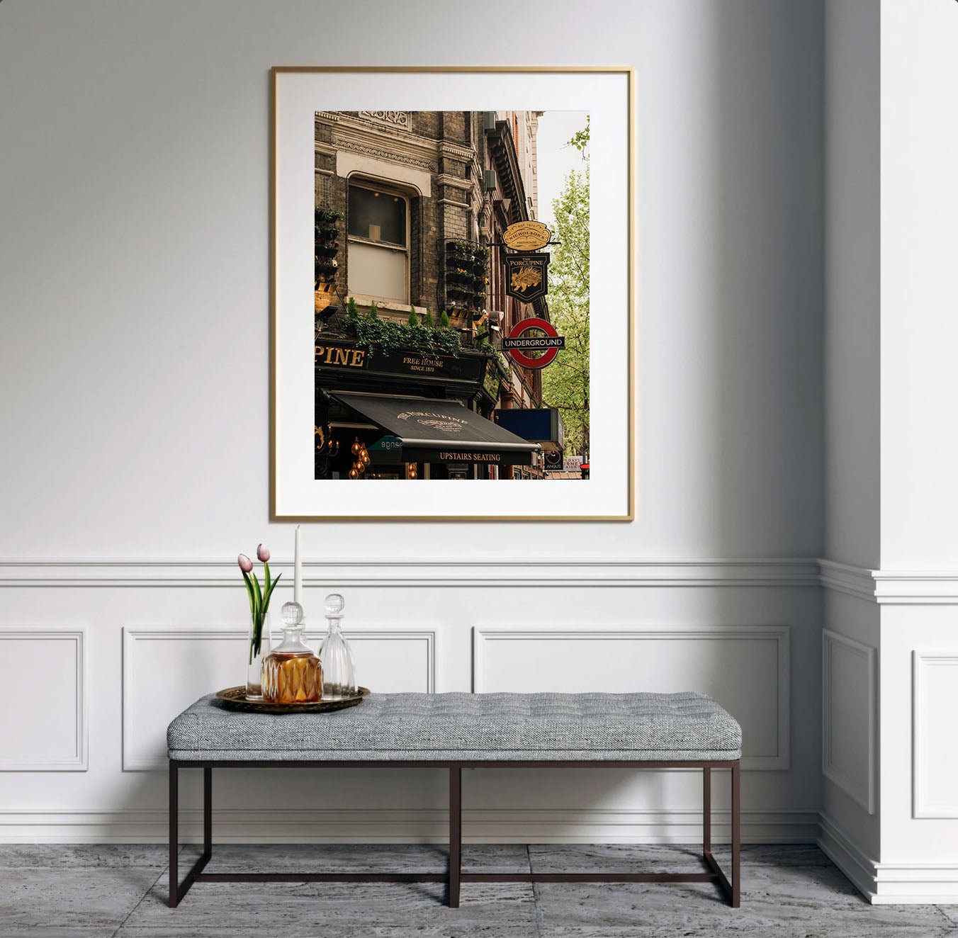 Framed "The Porcupine Pub" photo displayed above a bench with flowers and glassware in an elegant white room.