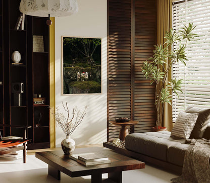 A cozy living room featuring Three Wise Ones art on the wall, a large plant, and sunlight streaming through the blinds onto a sofa and table.