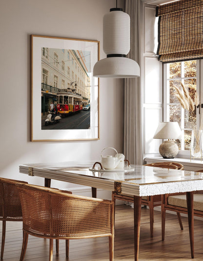 A dining room with a marble table, wicker chairs, and Tram 28—a large framed city street photo—on the wall.