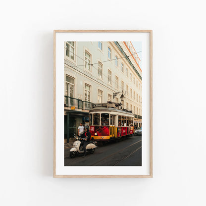 Framed photo titled Tram 28 features a yellow tram and a scooter rider before a light city building.