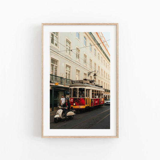 Framed photo titled Tram 28 features a yellow tram and a scooter rider before a light city building.