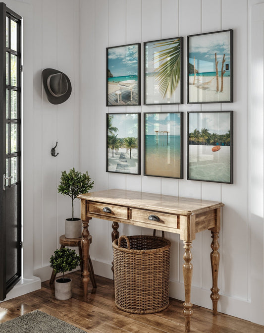 A wooden console table with a wicker basket, six Tropical Beach photos on the wall, and a hat by the door.