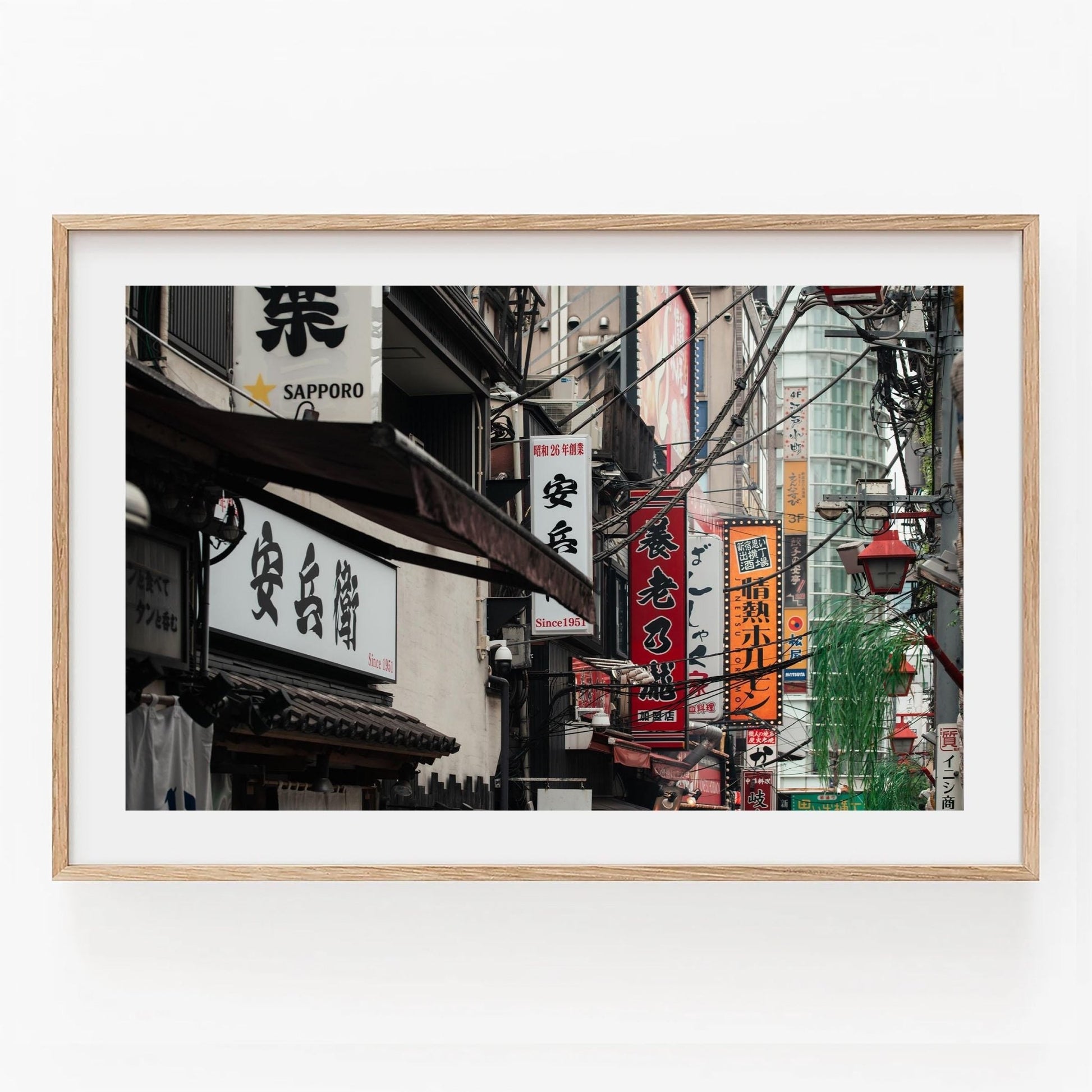 The Urban Tapestry is a framed photo capturing a busy Japanese street filled with vibrant signs and bustling activity.