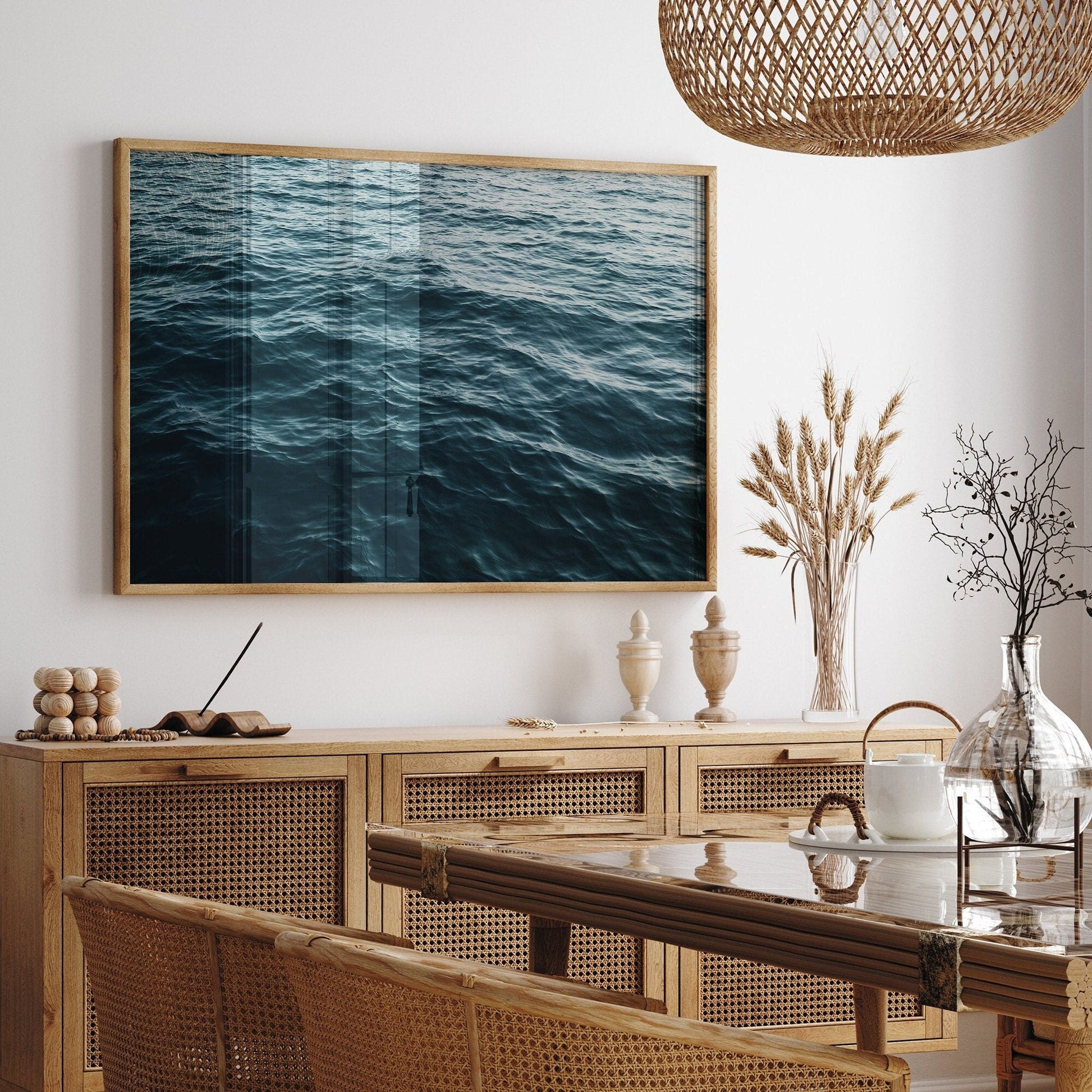 Dining room features wicker chairs, a wooden table, and the Water Ripples I framed photo. Natural decor adds coziness.