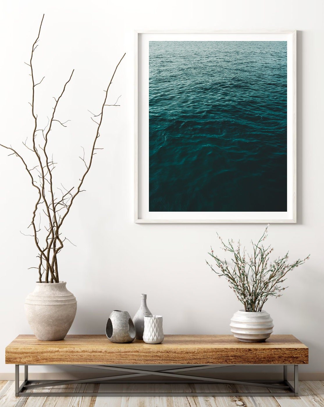 Minimalist room with Water Ripples II photo, two vases with branches, and small decor on a wooden bench.