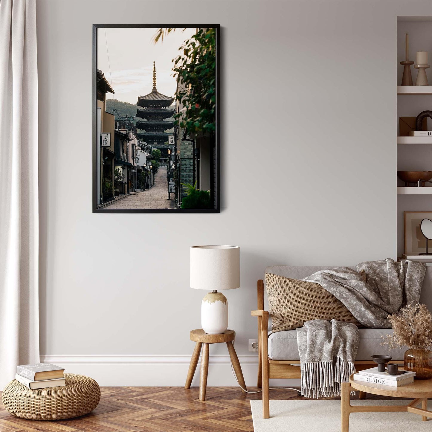 Minimalist living room featuring a framed Yasaka Pagoda At Sunrise photo on the wall, a beige sofa, and a small round table with a lamp.