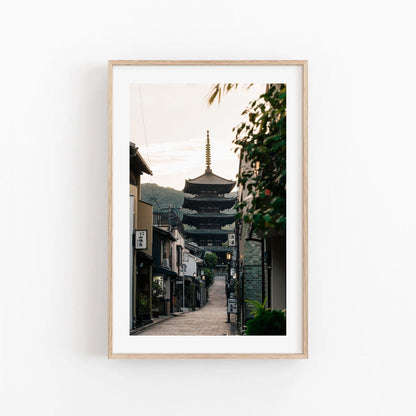 Framed photograph titled Yasaka Pagoda At Sunrise, featuring a pagoda lined with trees and buildings along a narrow street.