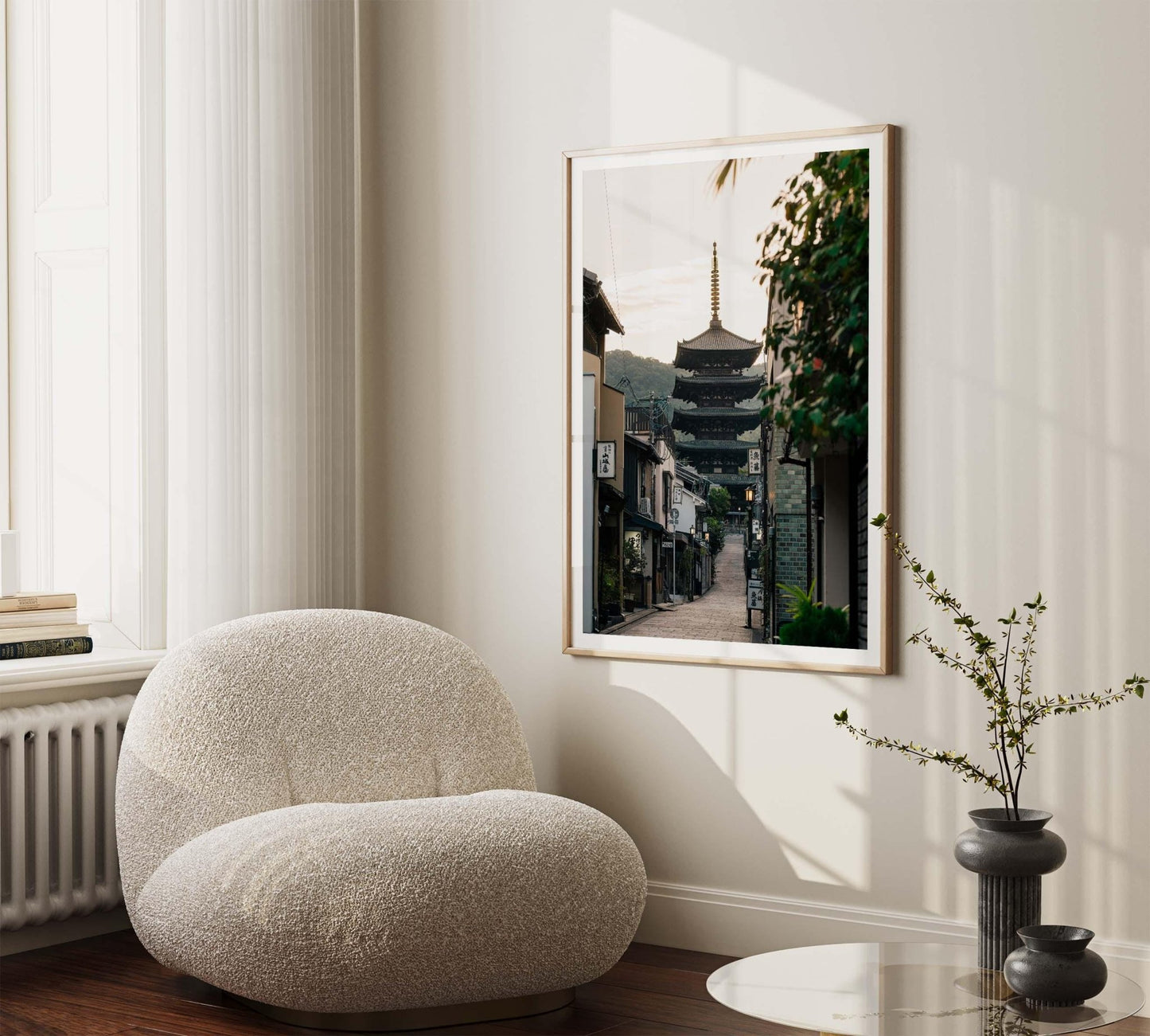 A minimalist room featuring a cozy chair and a framed photo titled Yasaka Pagoda At Sunrise, softly illuminated by natural light.