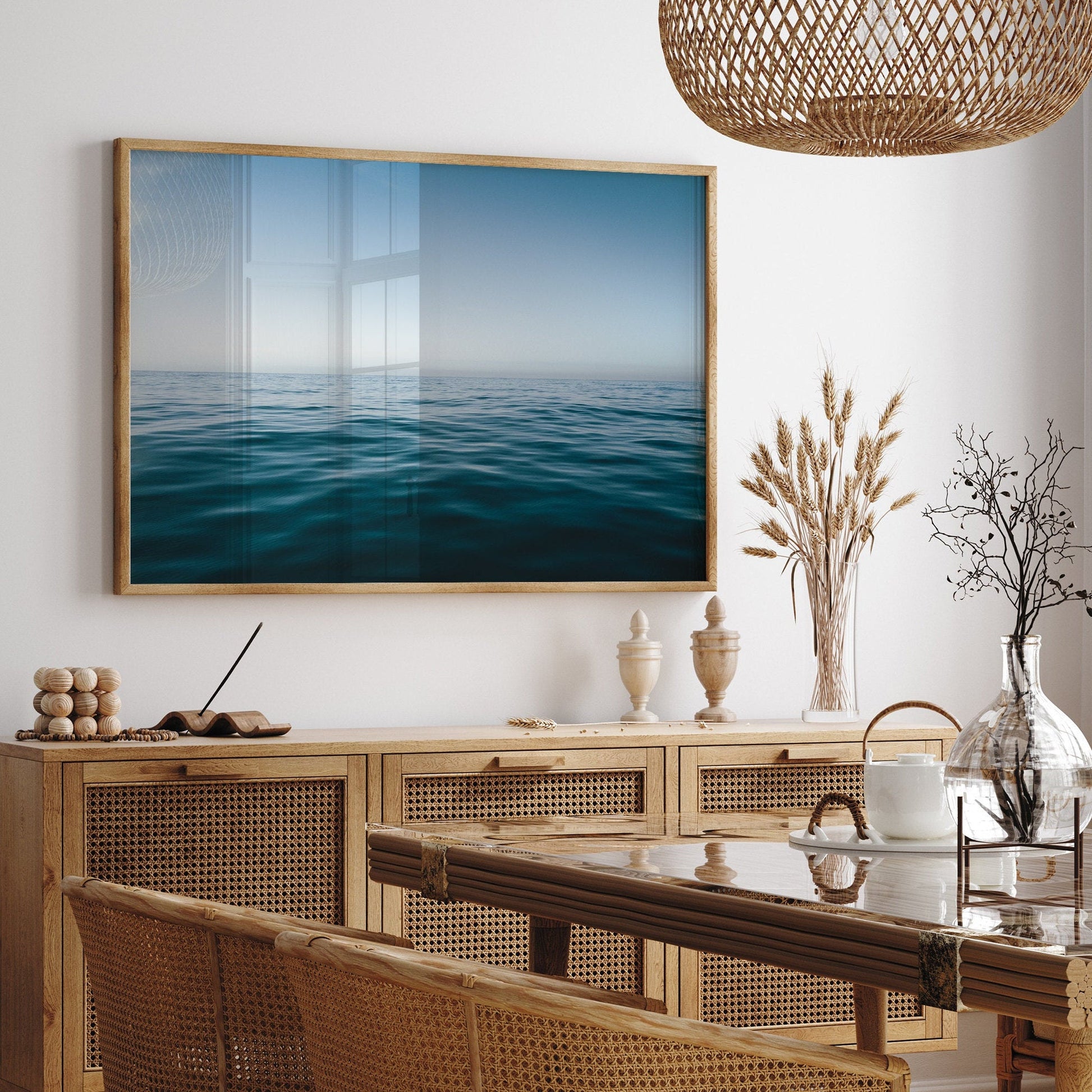 A dining room with a Zen Ocean table, wicker chairs, ocean artwork, and natural decor accents the space.