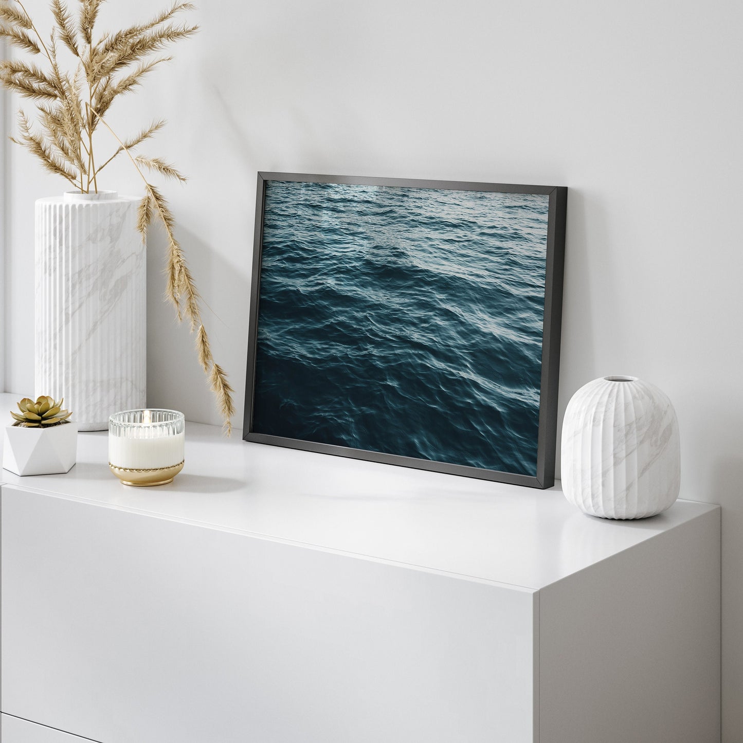 Photography of teal blue ocean water ripples close up in a black frame against white home decor.