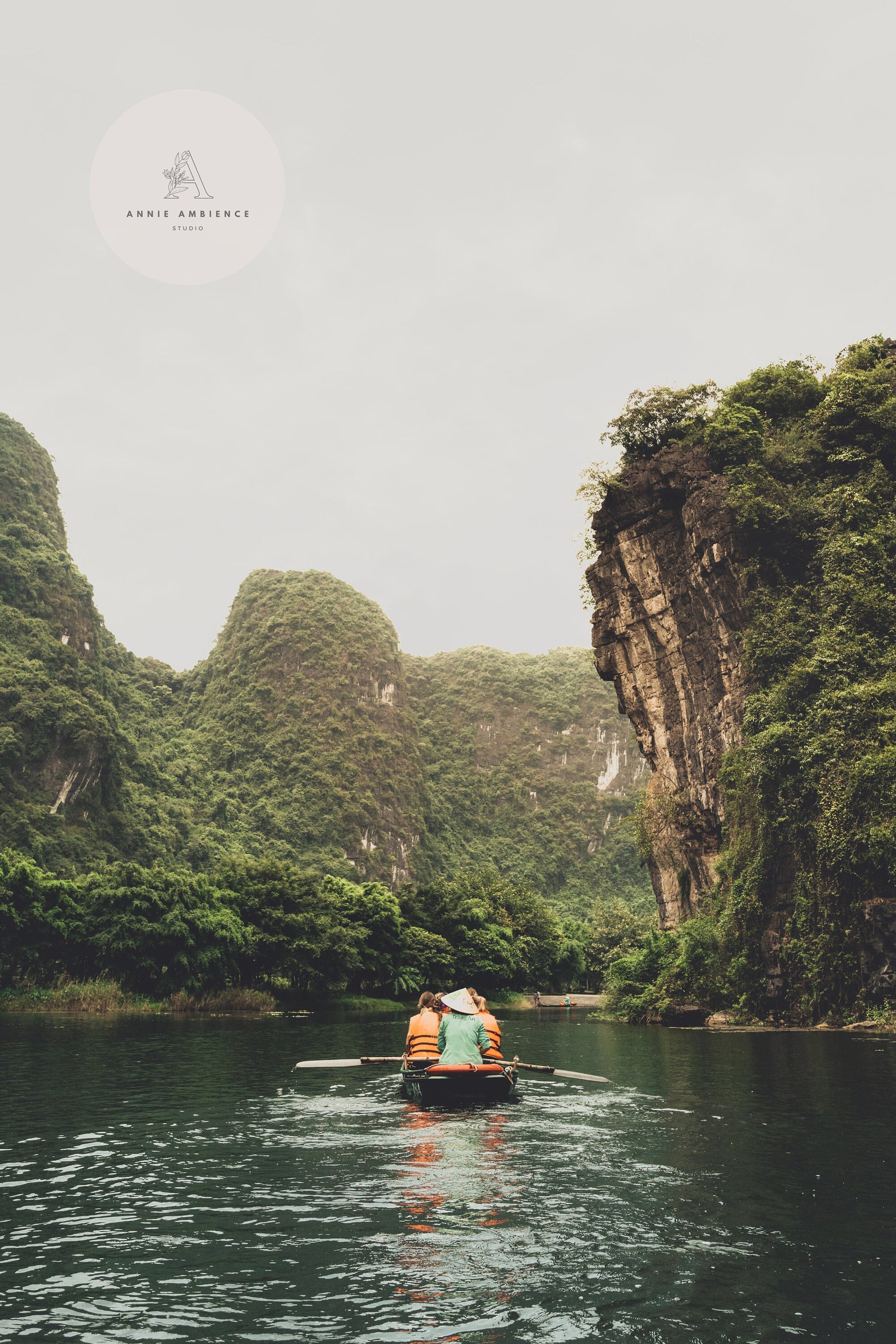 Small boat in the waterway between tall limestones in Ninh Binh, Vietnam.