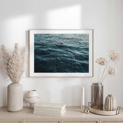 Framed photograph of teal blue ocean water ripples close up on the walls of a beige living room.