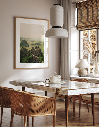 Stylish dining room with marble table, rattan chairs, white pendant light, and framed landscape art Hang Mua Peak I.